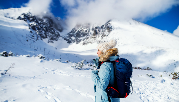 Side view portrait of happy smiling woman standing in snowy winter nature.