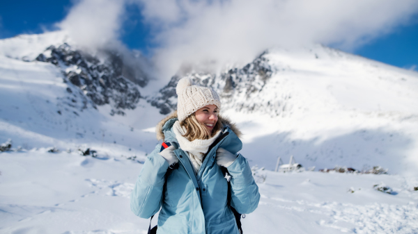 Front view portrait of happy smiling woman standing in snowy winter nature.