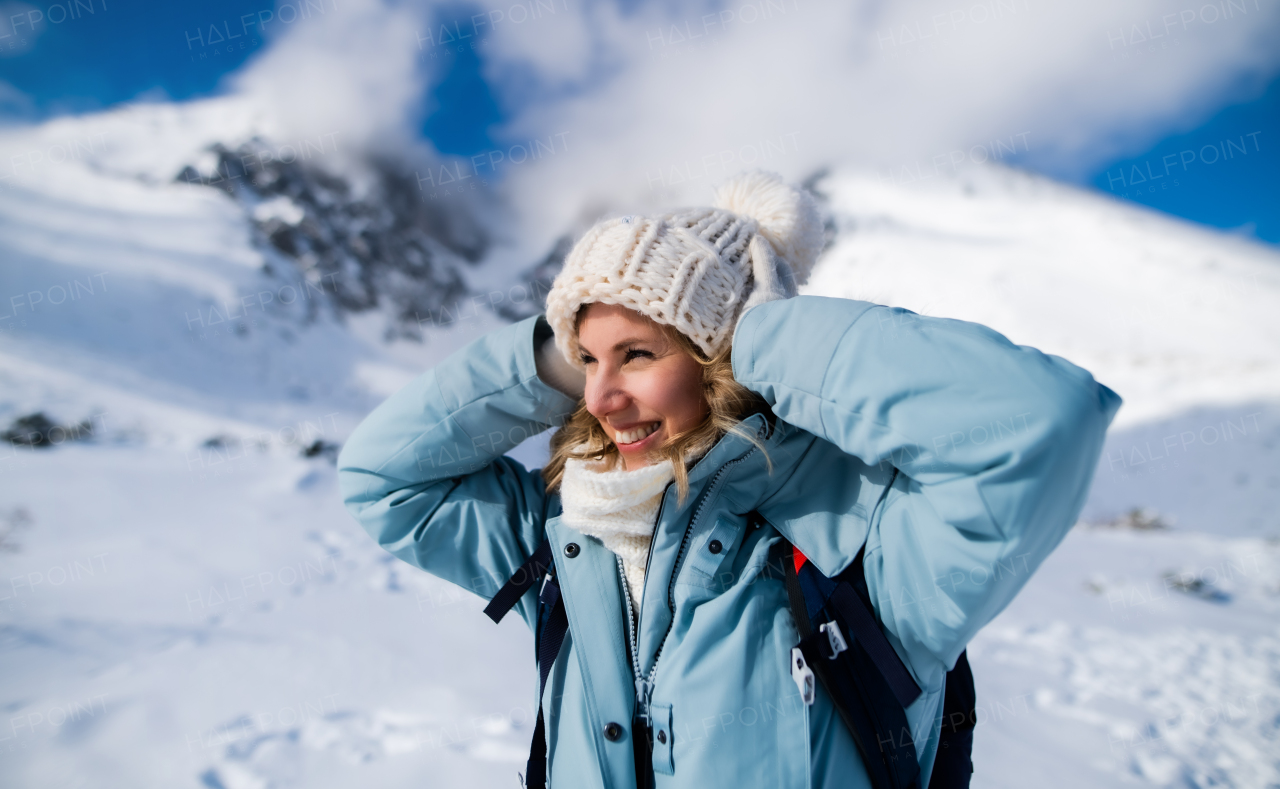 Front view portrait of happy smiling woman standing in snowy winter nature.