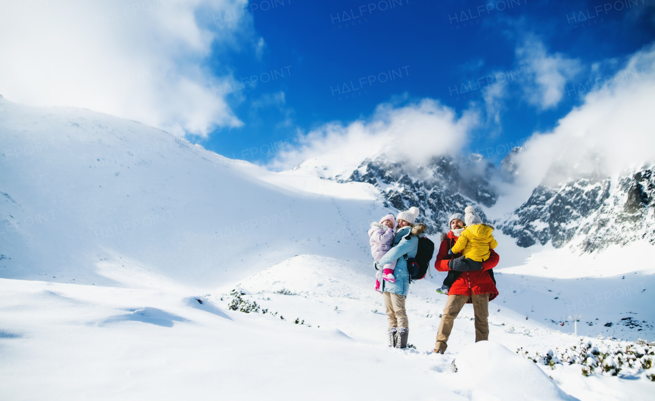 Front view portrait of father and mother with small son in winter nature, standing in the snow.