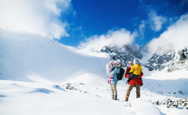 Front view portrait of father and mother with small son in winter nature, standing in the snow.