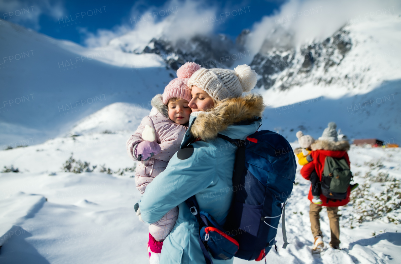 Portrait of mother with happy small daughter standing in winter nature, resting.