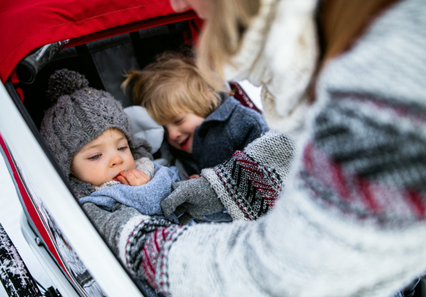 Midsection of unrecognizable mother with two small children in trailer in winter nature.