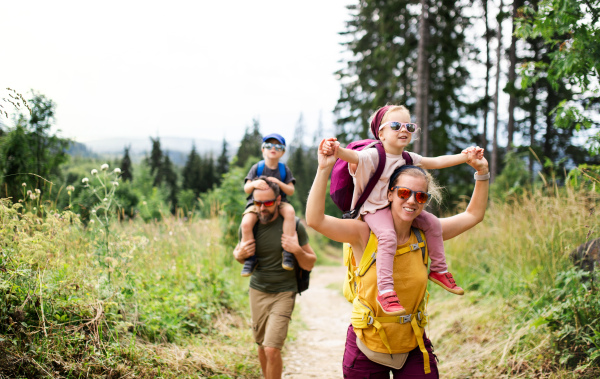 Front view of family with small children hiking outdoors in summer nature.