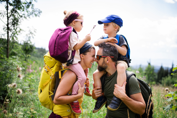 Front view of family with small children hiking outdoors in summer nature.