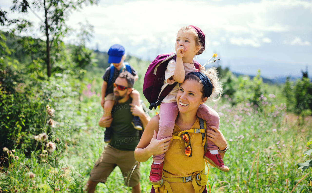 Front view of family with small children hiking outdoors in summer nature.