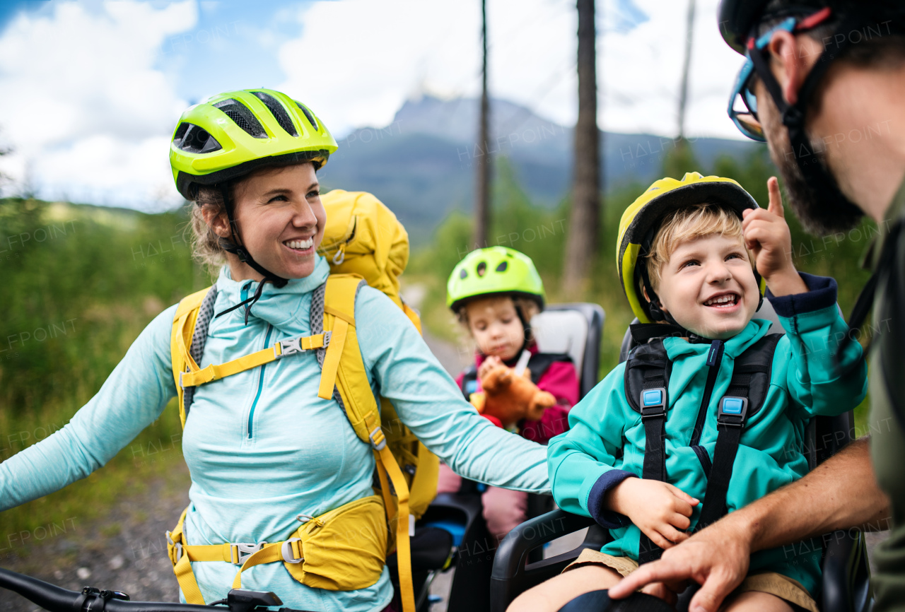 Happy family with small children cycling outdoors in summer nature.