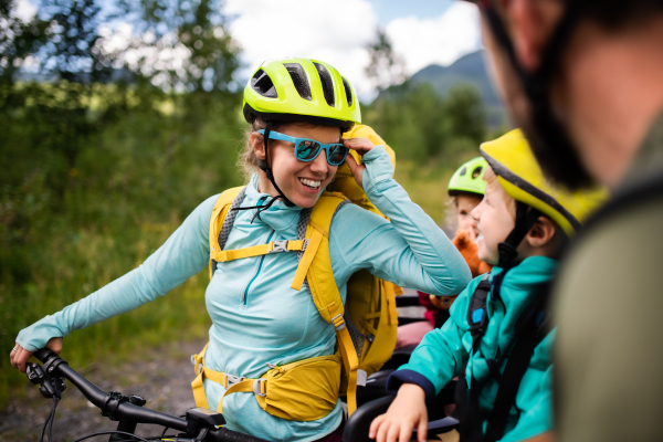 Happy family with small children cycling outdoors in summer nature.