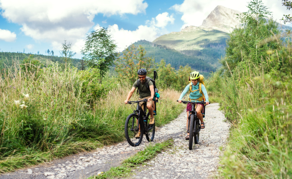 Happy family with small children cycling outdoors in summer nature.