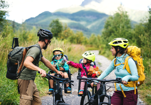 Happy family with small children cycling outdoors in summer nature, resting.