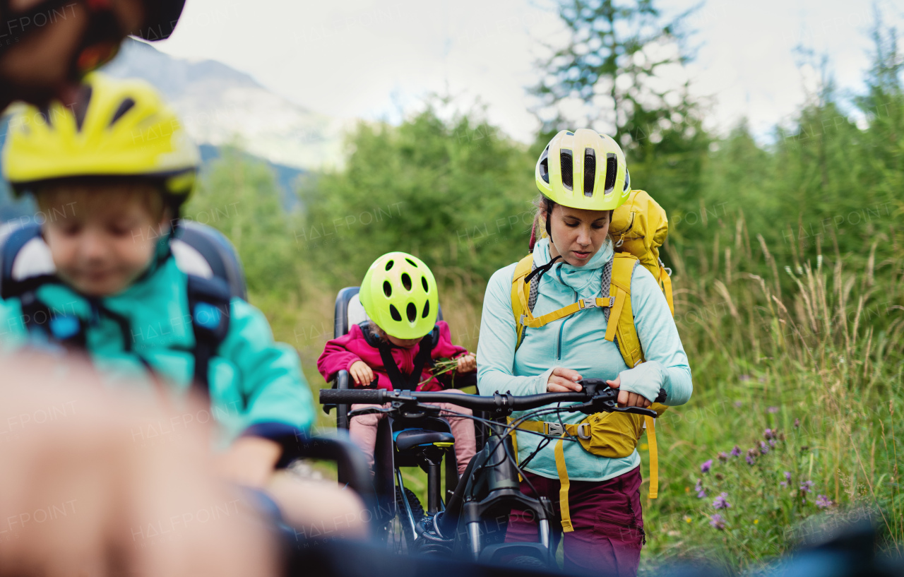 Happy family with small children cycling outdoors in summer nature, resting.