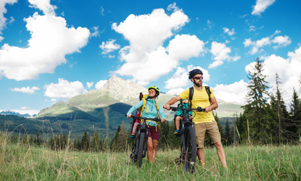 Happy family with small children cycling outdoors in summer nature, Tatra mountains Slovakia.