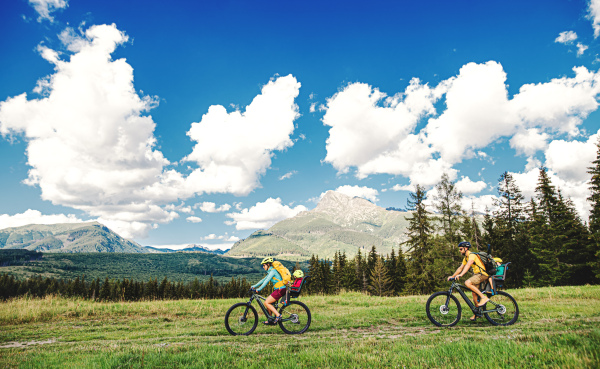 Happy family with small children cycling outdoors in summer nature.