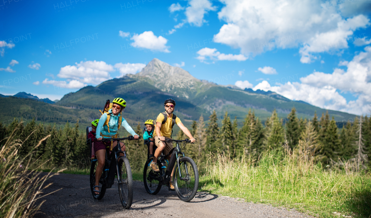 Happy family with small children cycling outdoors in summer nature.