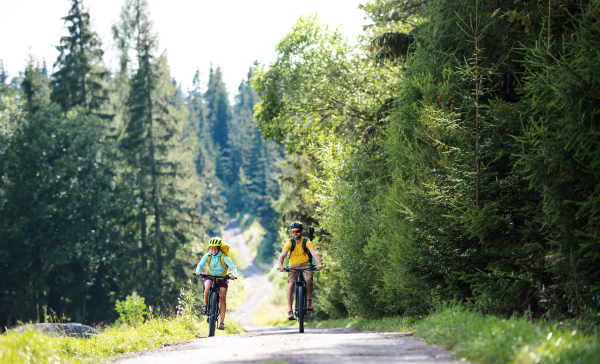 Happy family with small children cycling outdoors in summer nature.