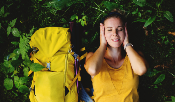 Top view of happy woman hiker lying on the ground outdoors in forest, resting.