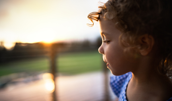 Close-up portrait of small girl outside at dusk, holiday in nature concept. Copy space.