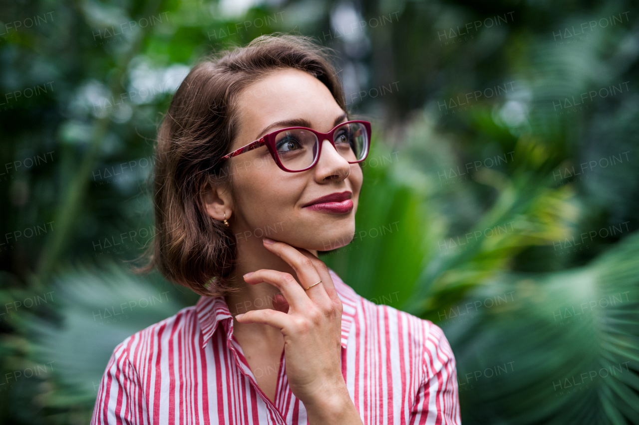 A young woman standing in botanical garden. Copy space.