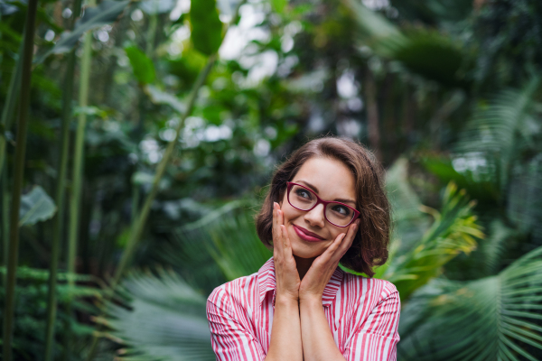 A young woman standing in botanical garden. Copy space.