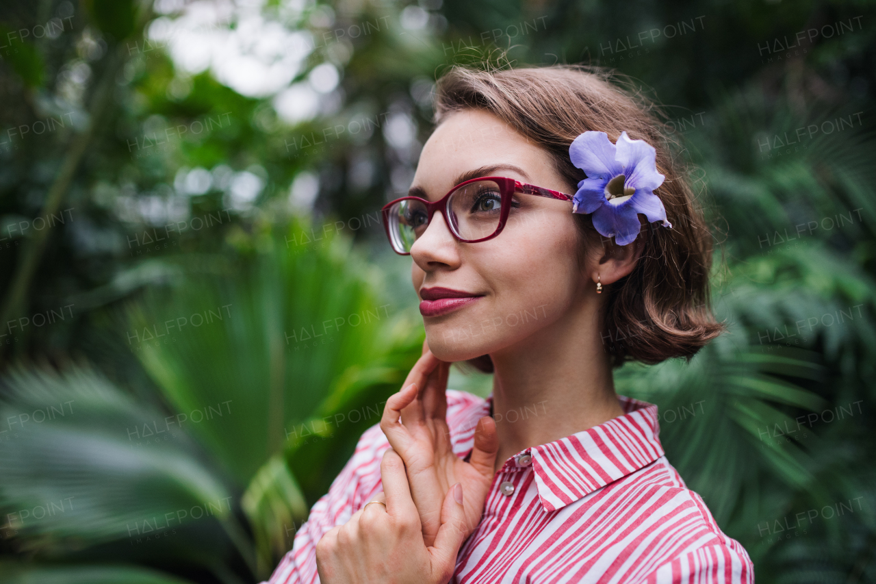 A young woman standing in botanical garden. Copy space.