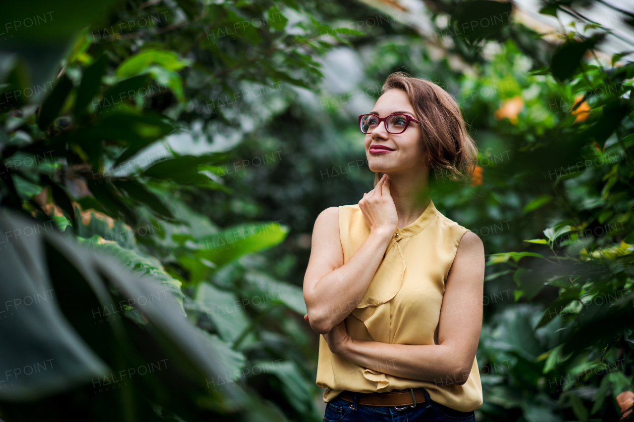 A young woman standing in botanical garden. Copy space.