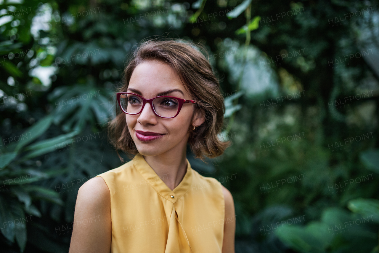 A young woman standing in botanical garden. Copy space.