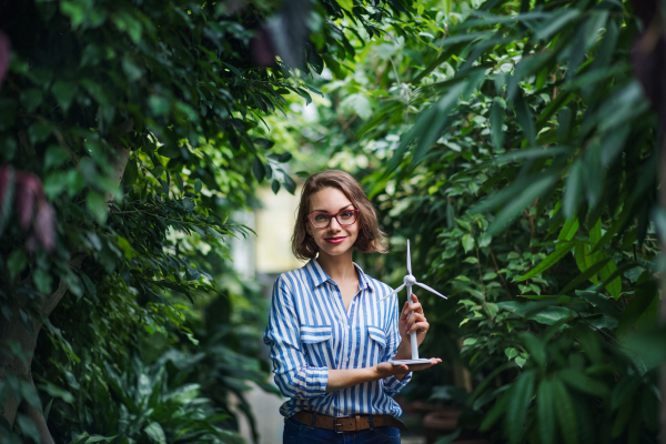 Young woman with windmill model standing in botanical garden. Copy space.