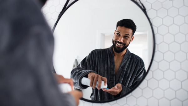 Portrait of young man using shaving gel indoors at home, morning or evening routine concept.