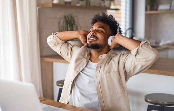 Portrait of young man student with laptop and headphones indoors at home, resting after studying.