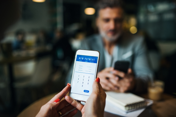 Midsection of unrecognizable business people with smartphone in a cafe, checking finances.