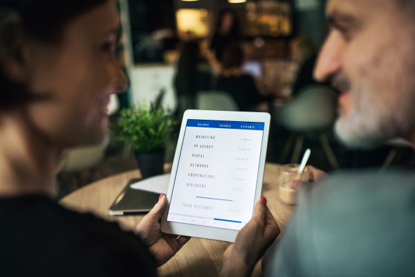 A midsection of man and woman having business meeting in a cafe, using tablet.
