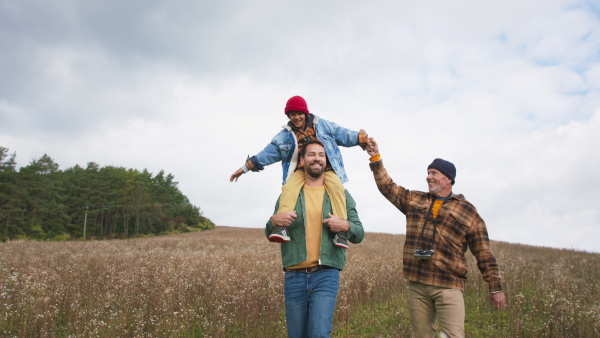 Three generations of men walking together at the meadow, discovering nature.