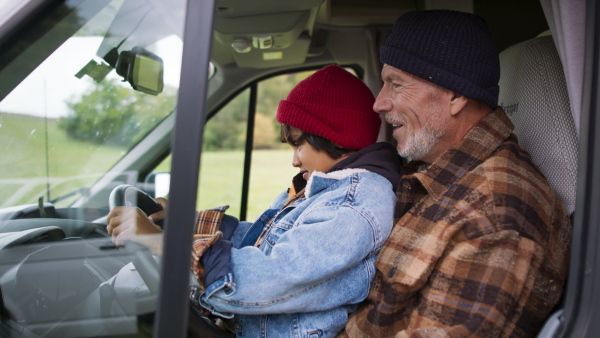 Grandfather teaching to drive car his grandson, having fun together.