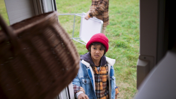 Grandfather, father and grandson preparing for picnic near their camper van. During autumn day.