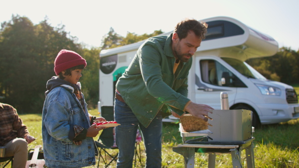 Three generations men spending time together during camping with camper van at autumn nature.