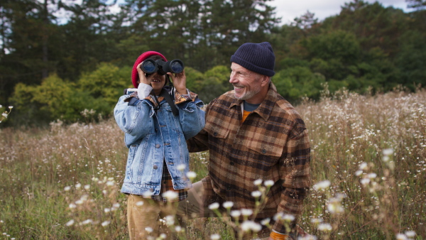 Senior man with his little grandson resting at autumn meadow during camping.