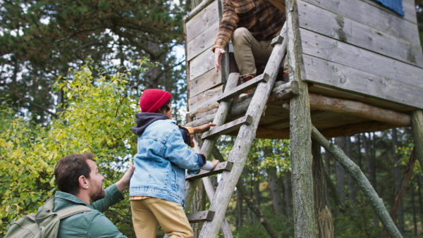 Grandfather, father and son having men time together in forest, sitting at a high hunter seat, climbing up.