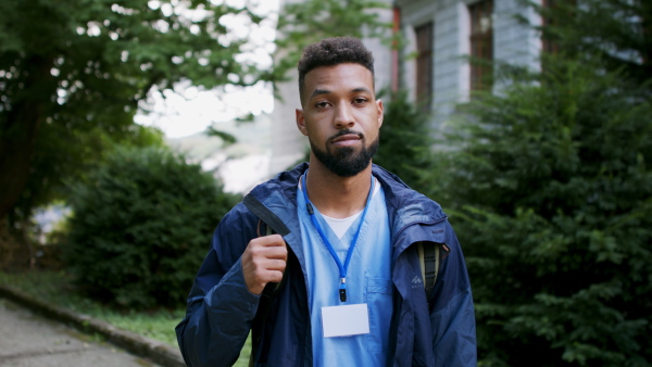 A man caregiver, male nurse or healthcare worker outdoors on the way to work, looking at camera.