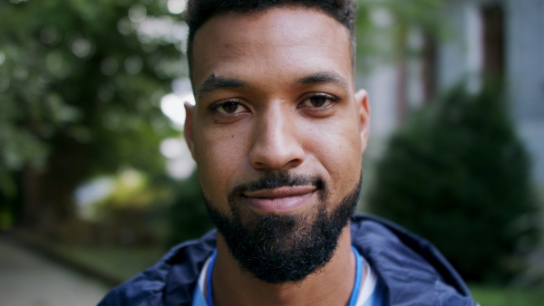 A close up of man caregiver, male nurse or healthcare worker outdoors on the way to work, looking at camera.