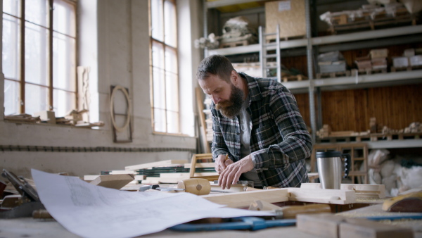 A male carpenter sketching desing of his product, looking at camera. Small business concept.