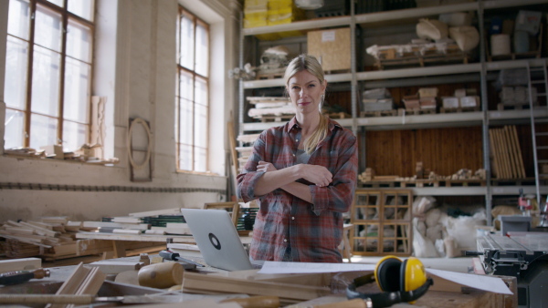 A female carpenter with laptop looking at camera. Small business concept.