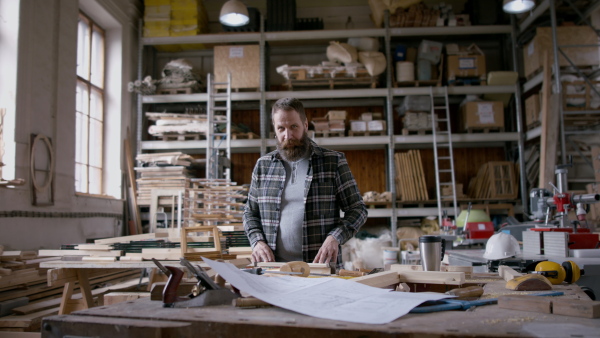 A male carpenter working on his product, looking at camera. Small business concept.