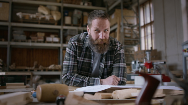 A male carpenter sketching desing of his product, looking at camera. Small business concept.