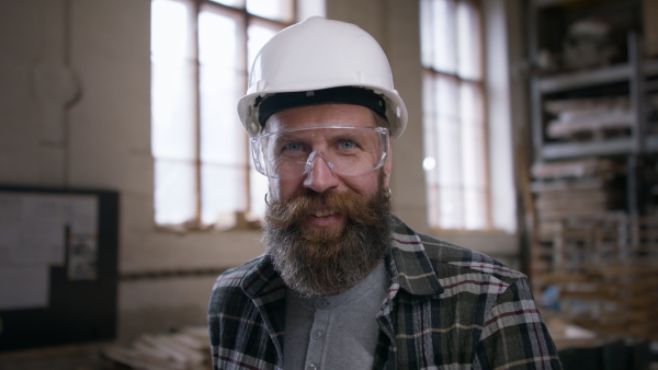 A male carpenter standing in workshop and looking at camera. Small business concept.