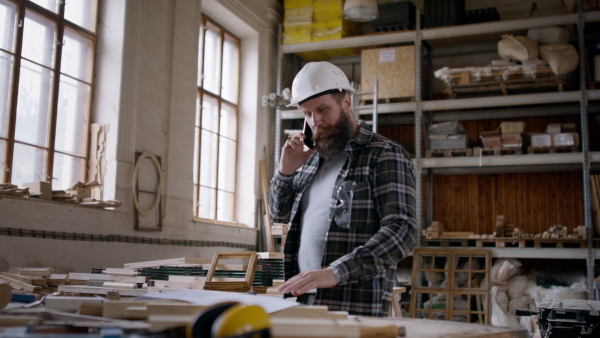 A male carpenter having a call, discussing desing of product. Small business concept.