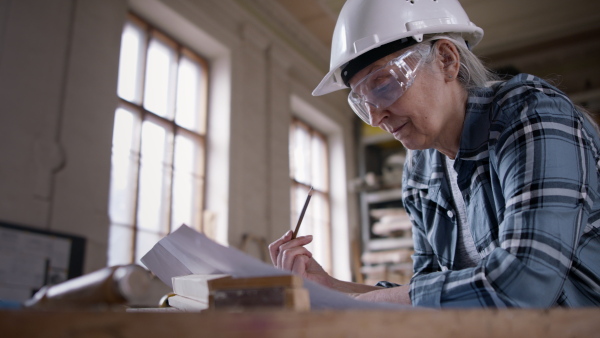 A senior female carpenter sketching design of her product. Small business concept.