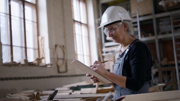 A senior female carpenter sketching design of her product. Small business concept.