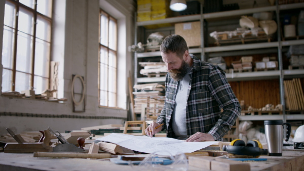 A male carpenter sketching desing of his product, looking at camera. Small business concept.