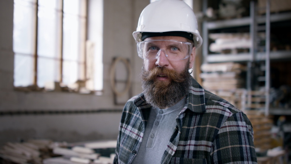 A male carpenter standing in workshop and looking at camera. Small business concept.