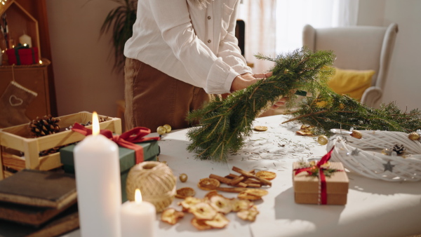 An unrecognizable senior woman making Christmas wreath from natural materials indoors at home